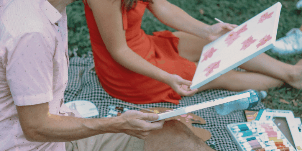 A couple on a date paint canvases in the park.