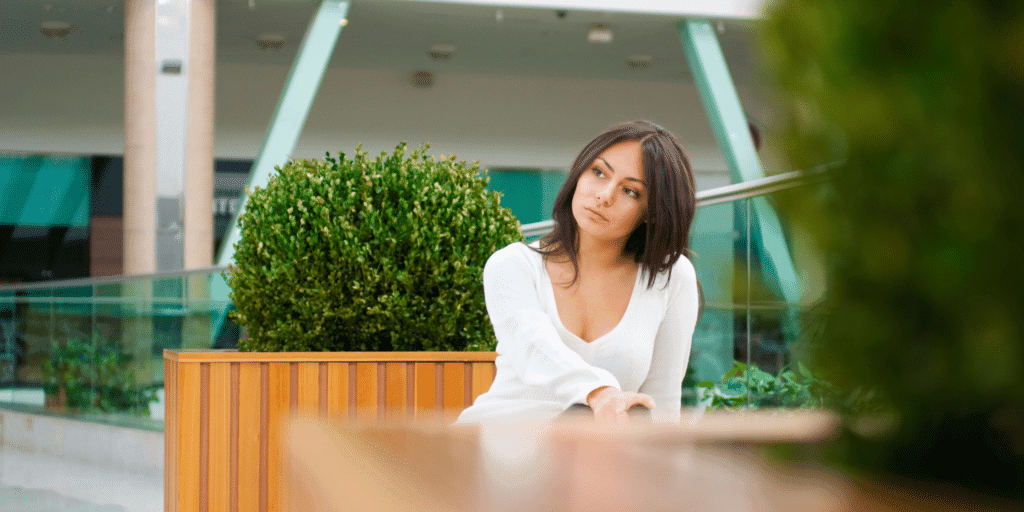 A single woman sits at a patio table alone waiting for a date who has stood her up, a sure sign that her date is not interested in her.