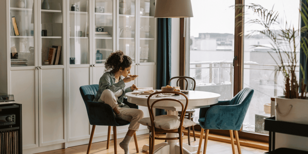 Young woman at breakfast table in her apartment feeling content with living the single life.