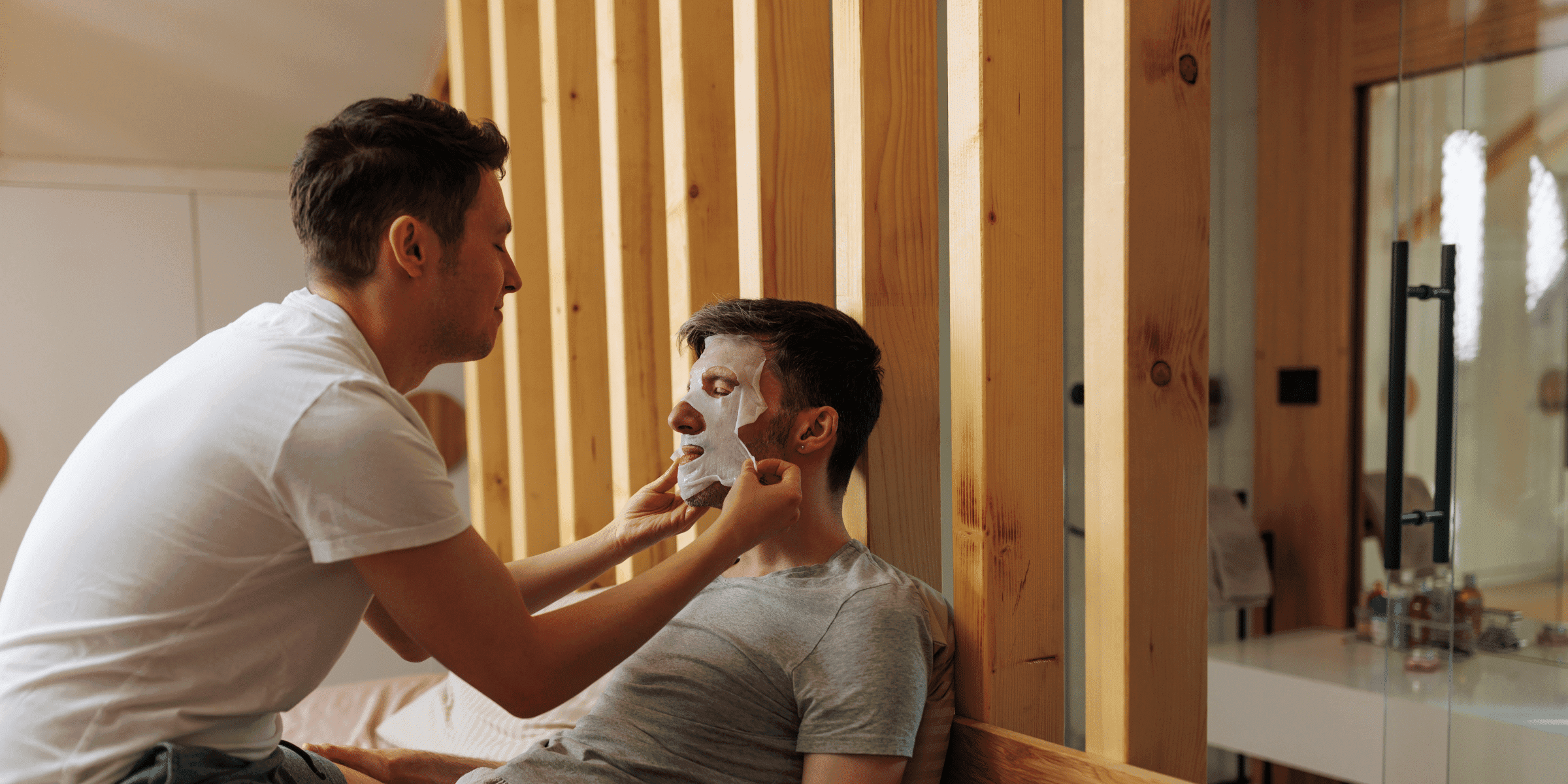 A male couple cares for each other by giving each other hydrating face masks as a gay dating tip.