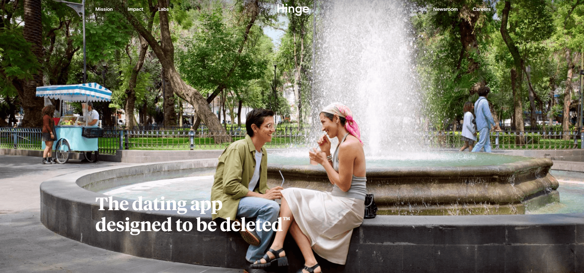 Hinge homepage showing a smiling couple chatting beside a park fountain with the tagline "The dating app designed to be deleted."