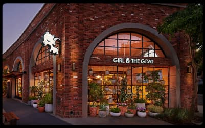Brick exterior and arched windows of Girl & The Goat restaurant in Chicago's West Loop at dusk