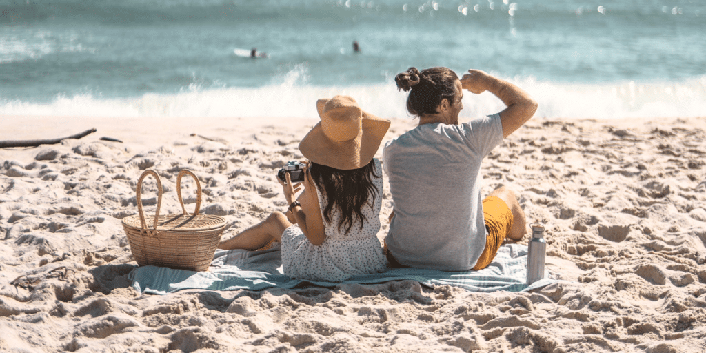 A man and woman having a picnic at the beach.