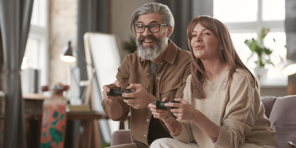 A mature man and woman playing video games on the couch.